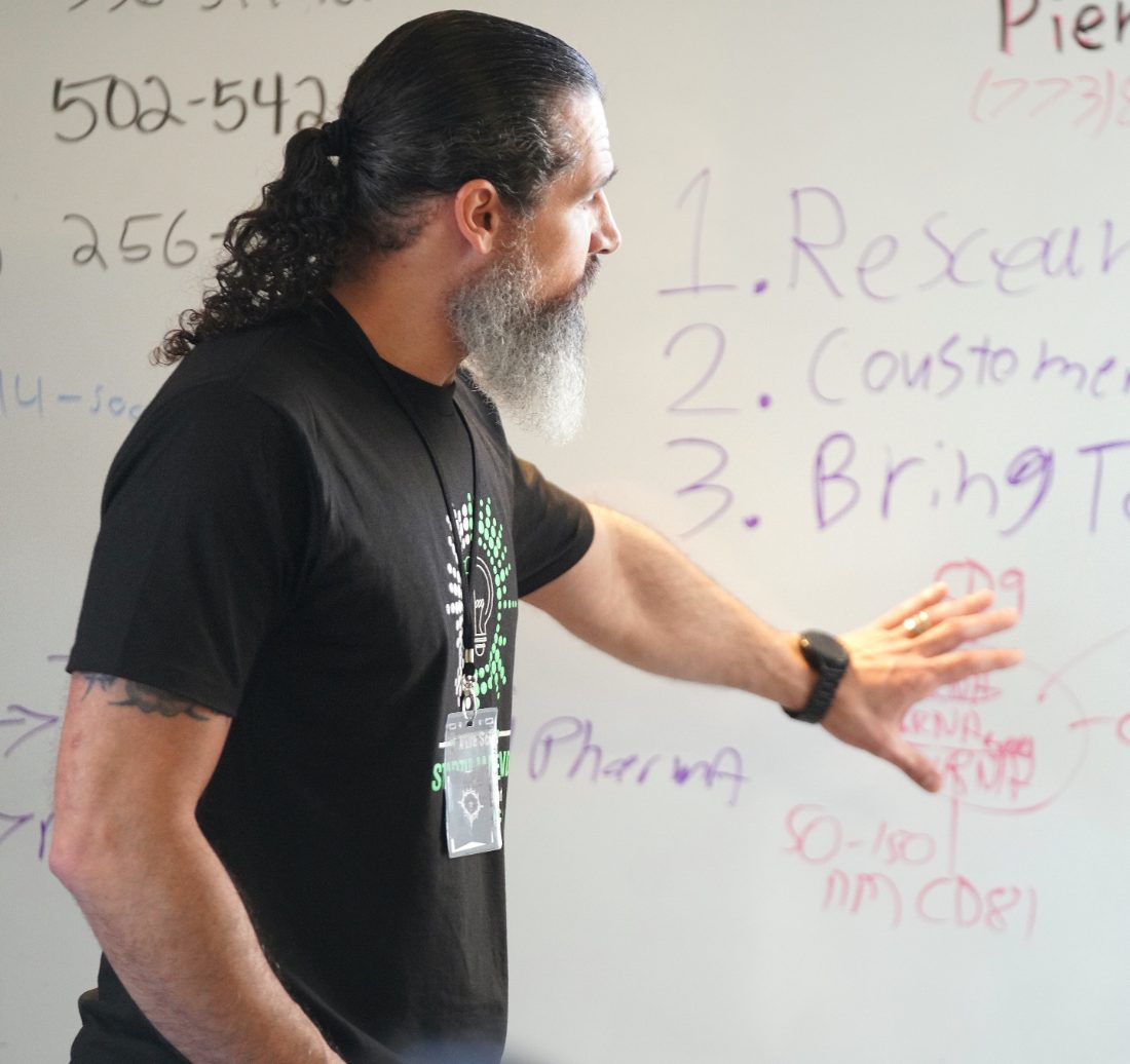 A Vision To Venture founder works through a startup problem at the whiteboard